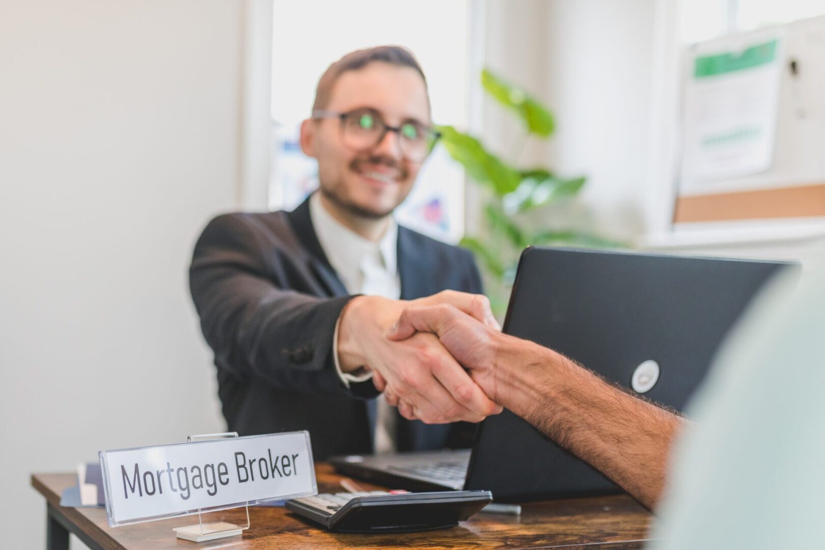 A man shaking hands over a laptop